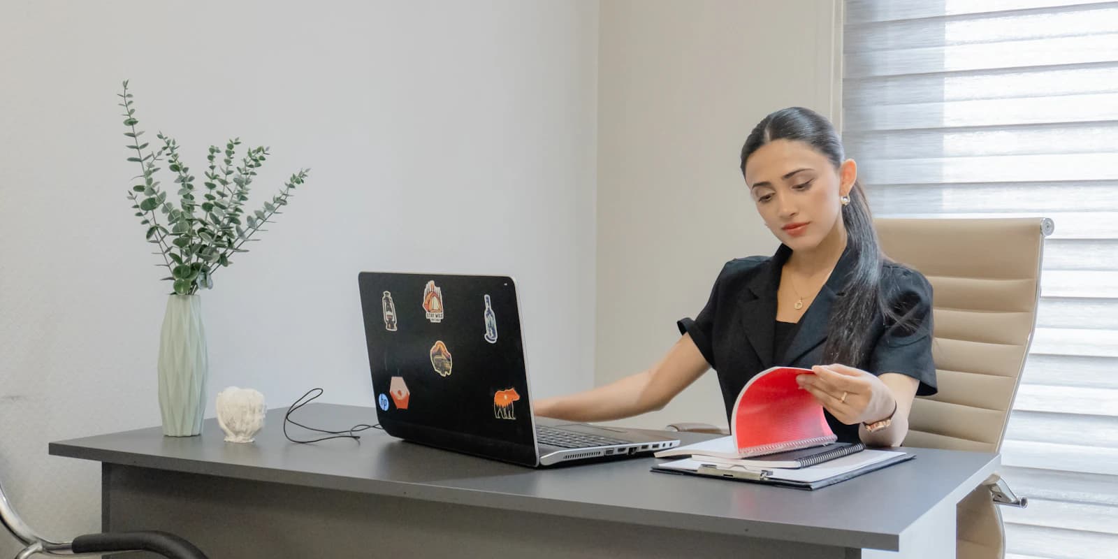 A hiring manager at her desk reading through a candidate's documents next to her laptop