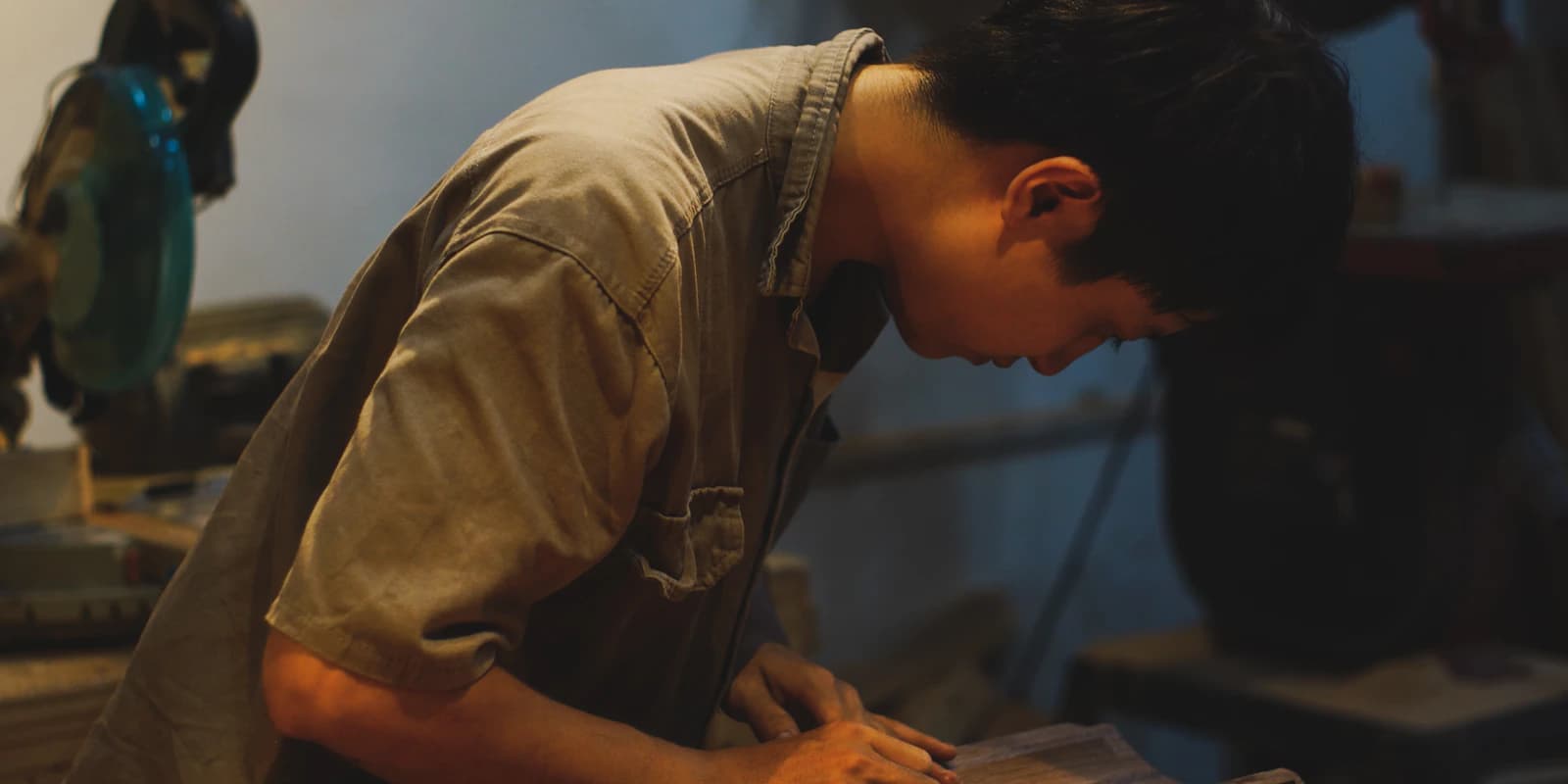 A craftsman bent over his workbench, demonstrating skill through the work itself